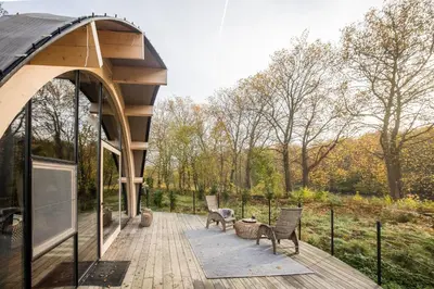 a wooden deck with two chairs and a building at Room8 luxury glamping in Huldenberg