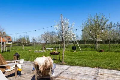 a yard with a park with a playground with sheep at Cabin Margot with hot tub in private garden in Kaprijke
