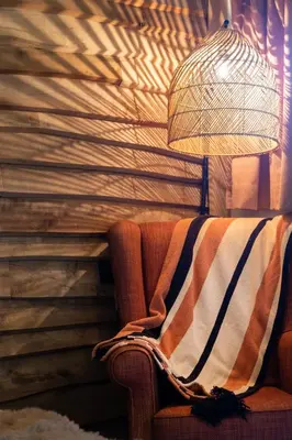 a blanket sitting on a couch with a lamp at Cabin Margot with hot tub in private garden in Kaprijke