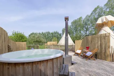 a hot tub in a backyard with a wooden fence at Cabin Margot with hot tub in private garden in Kaprijke