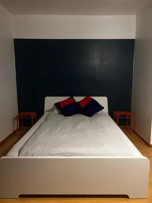 a white bed with two red and blue pillows on it at Apartment 202 in Ghent