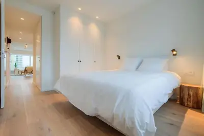 a bedroom with a large white bed and wooden floors at ANCHOR LODGE ANTWERP Unique Appartment view MAS! in Antwerp