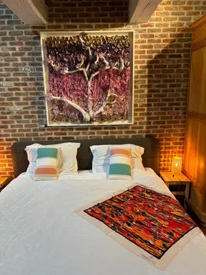 a bedroom with a bed with a painting on the wall at Karibu Keerbergen in Keerbergen