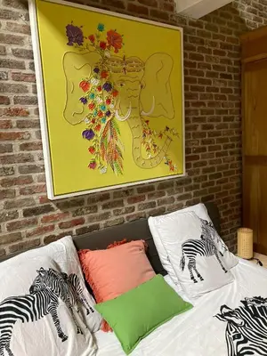 a bed with two pillows and a painting on the wall at Karibu Keerbergen in Keerbergen