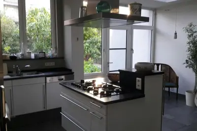 a kitchen with a stove top oven next to some windows at charming house with 3 bedrooms & terrace 10 minutes from city centre in Antwerp