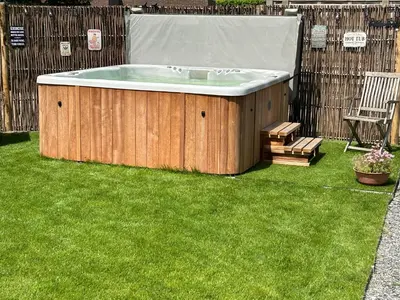a jacuzzi tub in a yard with a bench at CasaDeKaMa in Evergem