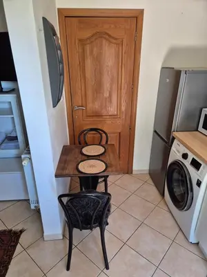 a small table and chair in a kitchen with a door at Studio équipé Brussels in Sint-Pieters-Leeuw
