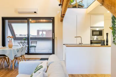 a kitchen and living room with a couch and a table at Loft Gent in Ghent
