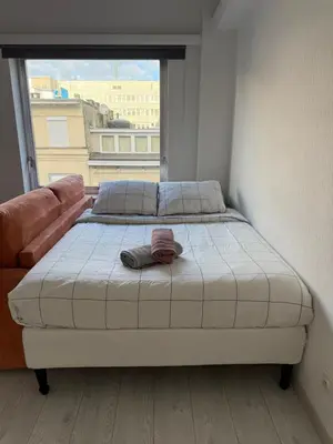 a bed in a room with a large window at Lovely condo next to European Area in Brussels
