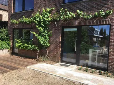 a brick building with windows and a wooden deck at 'het T-huisje' volledig ingerichte studio in Leuven