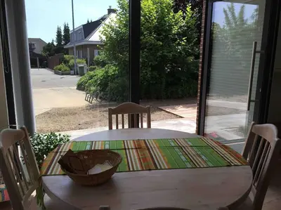 a table and chairs in a room with a window at 'het T-huisje' volledig ingerichte studio in Leuven