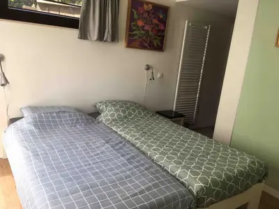 a bed in a bedroom with a blue comforter at 'het T-huisje' volledig ingerichte studio in Leuven