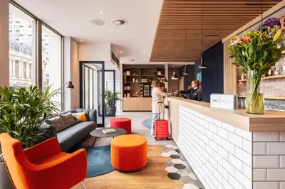 a lobby with a bar with orange chairs at Holiday Inn Express Antwerp - City Centre by IHG in Antwerp