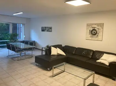 a living room with a black couch and a table at Superbe appartement lumineux et spacieux in Antwerp