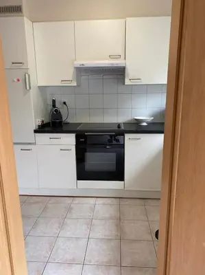 a kitchen with white cabinets and a black oven at Superbe appartement lumineux et spacieux in Antwerp
