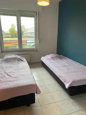 a bedroom with two beds and a window at Superbe appartement lumineux et spacieux in Antwerp