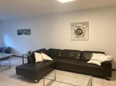 a living room with a black couch and a table at Superbe appartement lumineux et spacieux in Antwerp