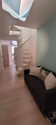 a living room with a couch and a spiral staircase at Bruxelles ma belge in Brussels