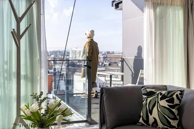 a man standing on a balcony looking out the window at L-Avenue in Brussels