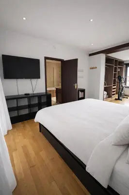 a bedroom with a large white bed and a flat screen tv at Spacious Villa in Dilbeek with Private Garden, Ideal for Families & Business in Dilbeek