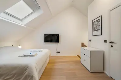 a white bedroom with a bed and a dresser at Mooie vernieuwde Duplex in hartje Gent , Patershol in Ghent