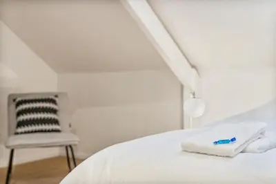 a bedroom with a white bed and a chair at Mooie vernieuwde Duplex in hartje Gent , Patershol in Ghent