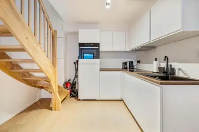 a kitchen with white cabinets and a staircase at Mooie vernieuwde Duplex in hartje Gent , Patershol in Ghent