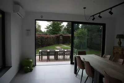 a dining room with a large glass door with a table and chairs at Vakantiewoning Den Appel in Dendermonde