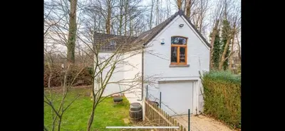 a small white house with a garage in a yard at Cosy little house in Kraainem