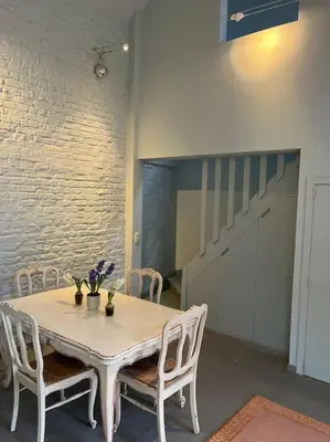 a white table and chairs in a room with a staircase at Cosy little house in Kraainem