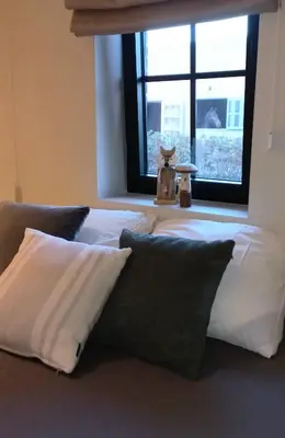 a bed with white sheets and pillows in front of a window at 'De Zandrug' vakantiehoeve - B&B in Stekene