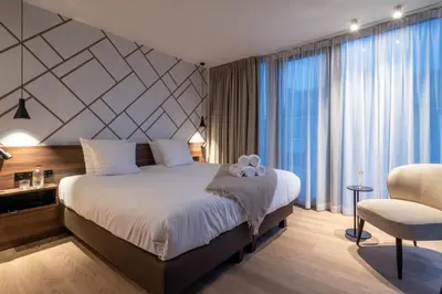 a bedroom with a large bed and a chair at ONE TWO FOUR - Hotel & Spa in Ghent