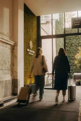 two women walking down a sidewalk with their luggage at ONE TWO FOUR - Hotel & Spa in Ghent