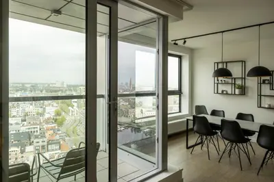 a dining room with a table and chairs and large windows at UNIEK appartement - mooiste en hoogste uitzicht op Antwerpen! - incl gratis parking in Antwerp