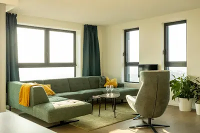 a living room with a green couch and a chair at UNIEK appartement - mooiste en hoogste uitzicht op Antwerpen! - incl gratis parking in Antwerp