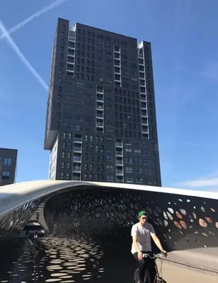 a man riding a bike under a bridge with a tall building at UNIEK appartement - mooiste en hoogste uitzicht op Antwerpen! - incl gratis parking in Antwerp