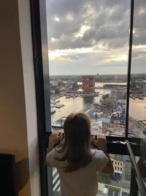 a woman looking out of a window at a city at UNIEK appartement - mooiste en hoogste uitzicht op Antwerpen! - incl gratis parking in Antwerp