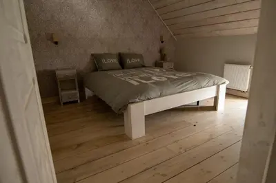 a large bed in a room with a wooden floor at Bed and Breakfast Paellepelhoeve in Ninove