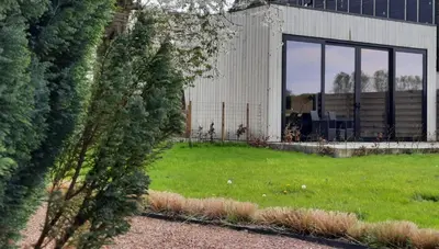 a building with glass windows and a green yard at Station 25A in Duffel