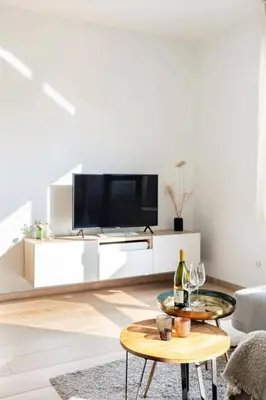 a white living room with a tv and a table at Sunny haven in Antwerp