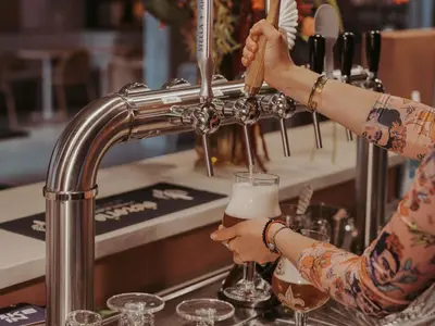 a woman is pouring a drink into a glass at Adagio Access Gent Centrum Dampoort in Ghent