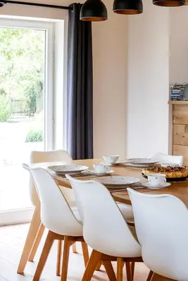 a dining room with a wooden table and white chairs at 't Jongehof in Zaffelare