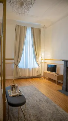 a living room with a large window and a table at Hotel de Maître de Vaughan in Brussels