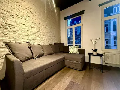 a couch in a living room with a brick wall at Luxury Suites Princess by Rikas Hotels in Antwerp