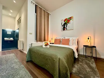 a bedroom with a large bed with a green blanket at Luxury Suites Centrum by Rikas Hotels in Antwerp