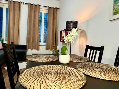 a dining room table with four chairs and a table with flowers at Luxury Suites Centrum by Rikas Hotels in Antwerp
