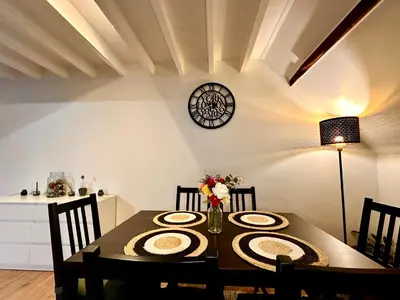a dining room table with chairs and a clock on the wall at Luxury Suites Centrum by Rikas Hotels in Antwerp