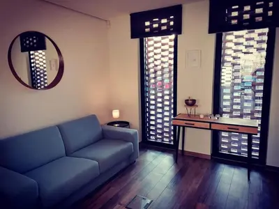 a living room with a blue couch and some windows at Vakantievilla met jacuzzi Limburg in Kwaadmechelen
