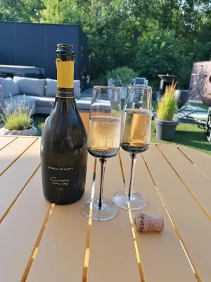 two glasses of wine on a picnic table with a bottle of wine at Vakantievilla met jacuzzi Limburg in Kwaadmechelen
