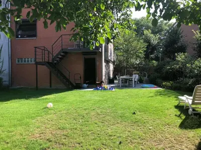 a yard with a staircase and a dog sitting on the grass at Privé kamer met gedeelde badkamer - rand Antwerpen - afrit E313 Wommelgem in Antwerp